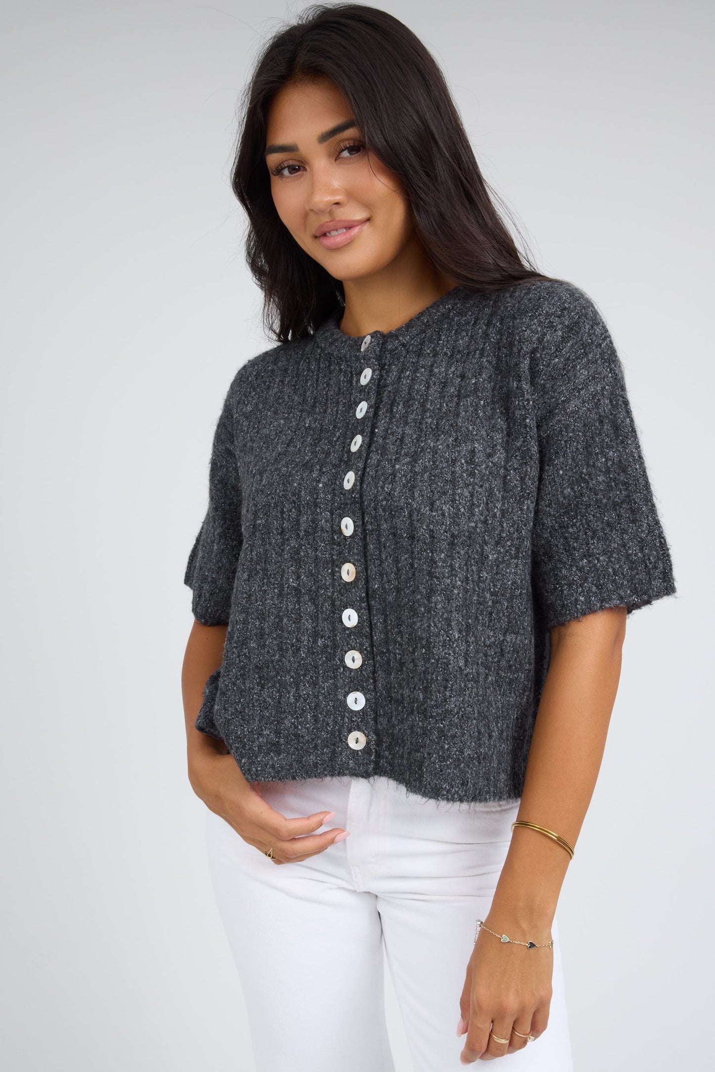 Young woman wearing a modest wide rib button down cardigan with white buttons, and short sleeves.
