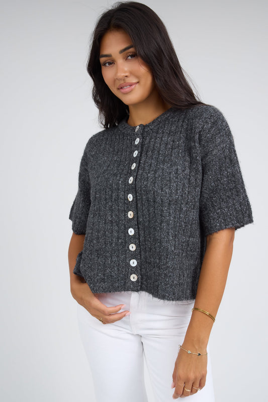 Young woman wearing a modest wide rib button down cardigan with white buttons, and short sleeves.