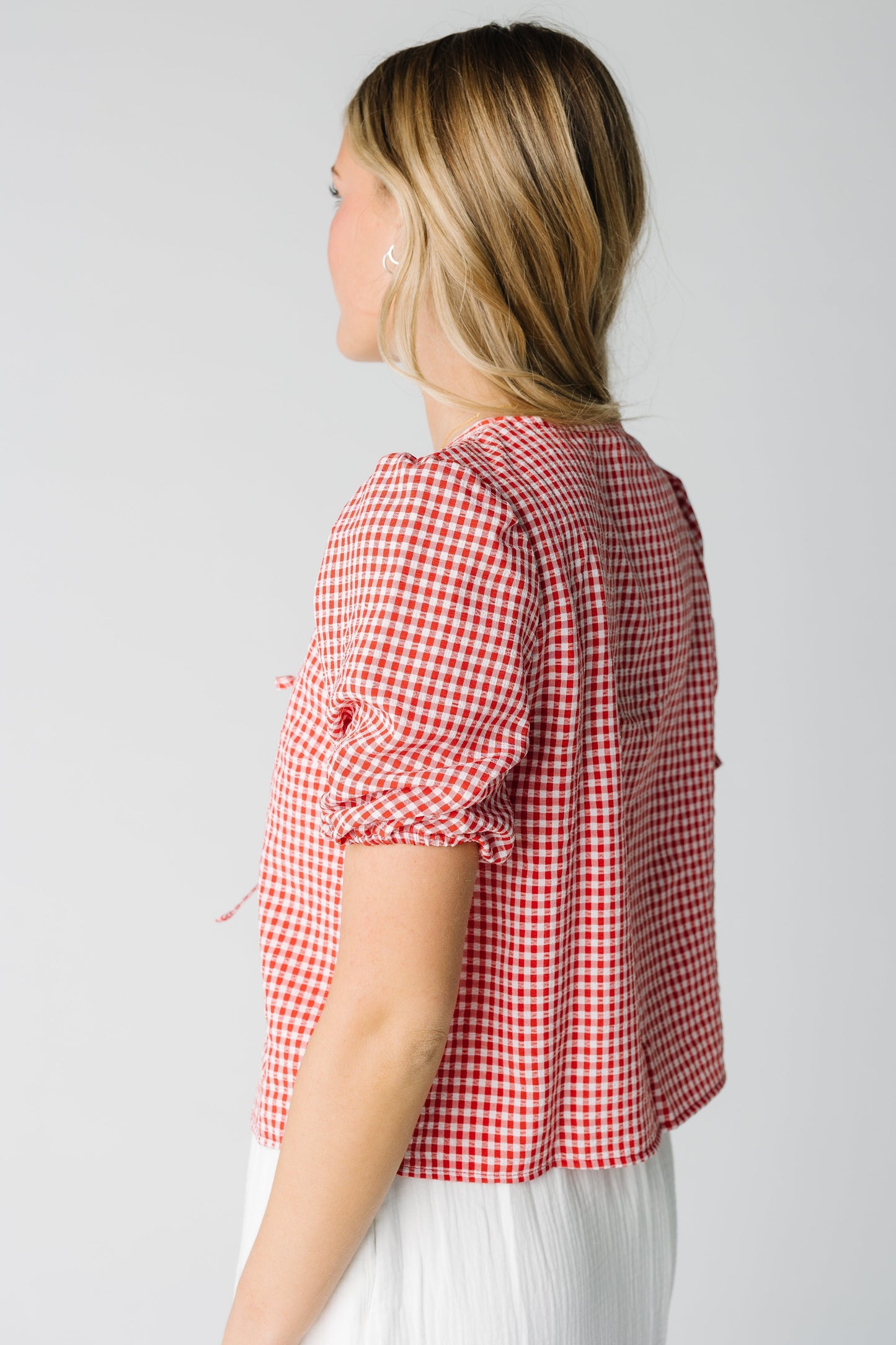 Side view of red and white gingham short puff sleeve top