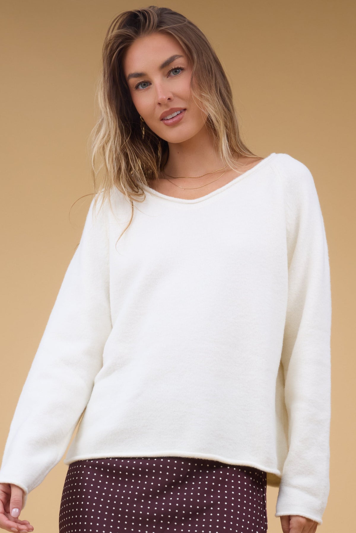 Young woman wearing a modest loose fitting sweater witha rolled V-neckline.