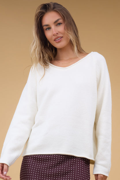 Young woman wearing a modest loose fitting sweater witha rolled V-neckline.