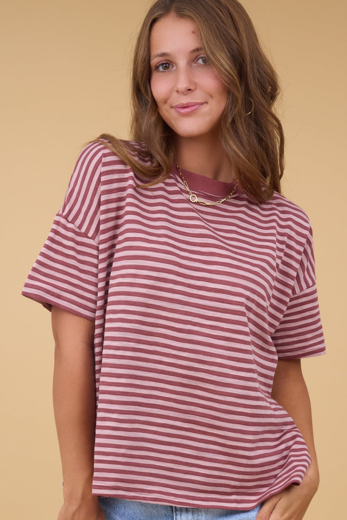 Young woman wearing a mauve & pink stripe, short sleeve stripe tee with a crew neckline.