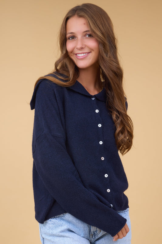 A young woman wearing a modest navy button down cardigan with a wide sailor collarand long sleeves.