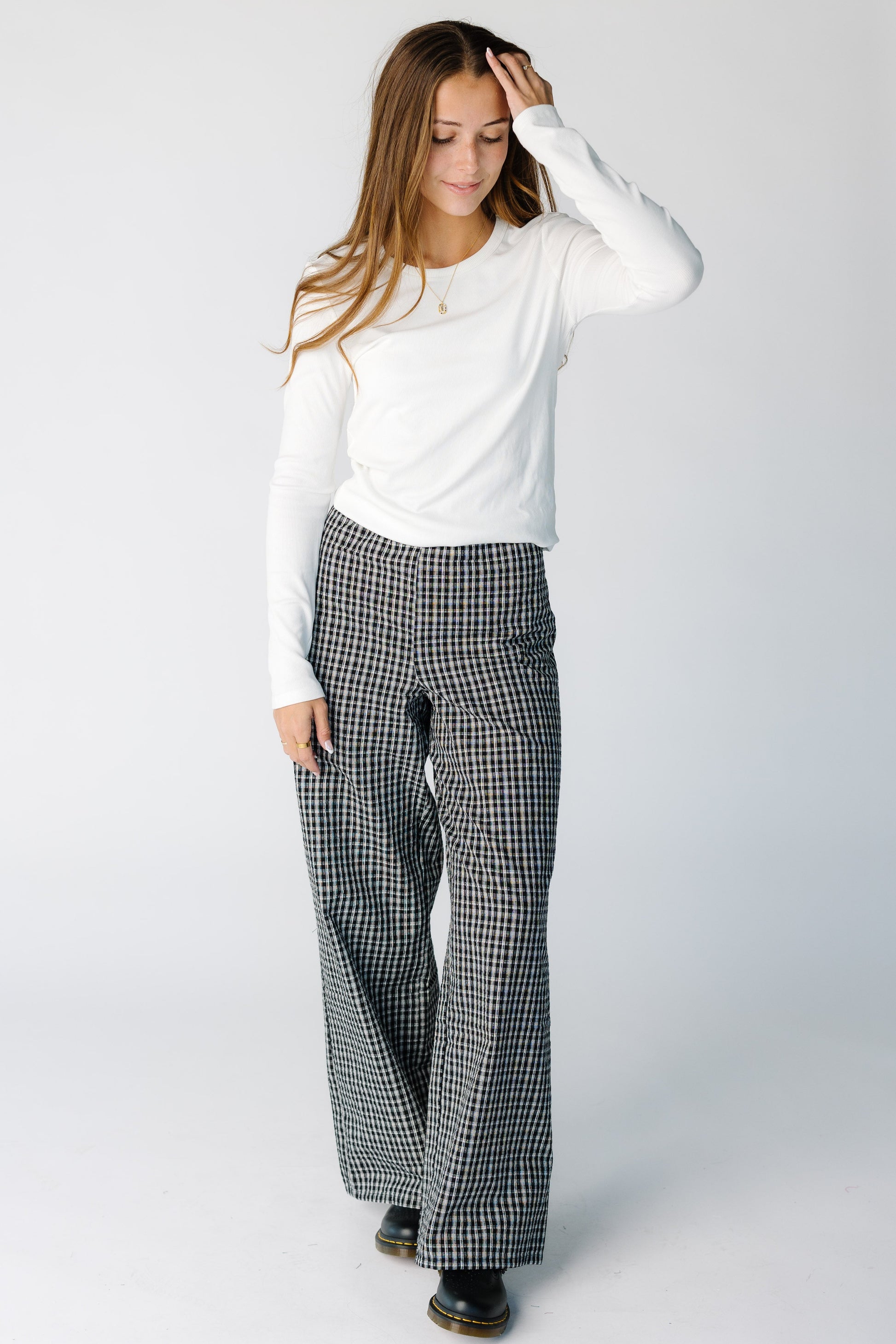 Woman wearing a modest black plaid pair of pants with wide cut leg and medium rise