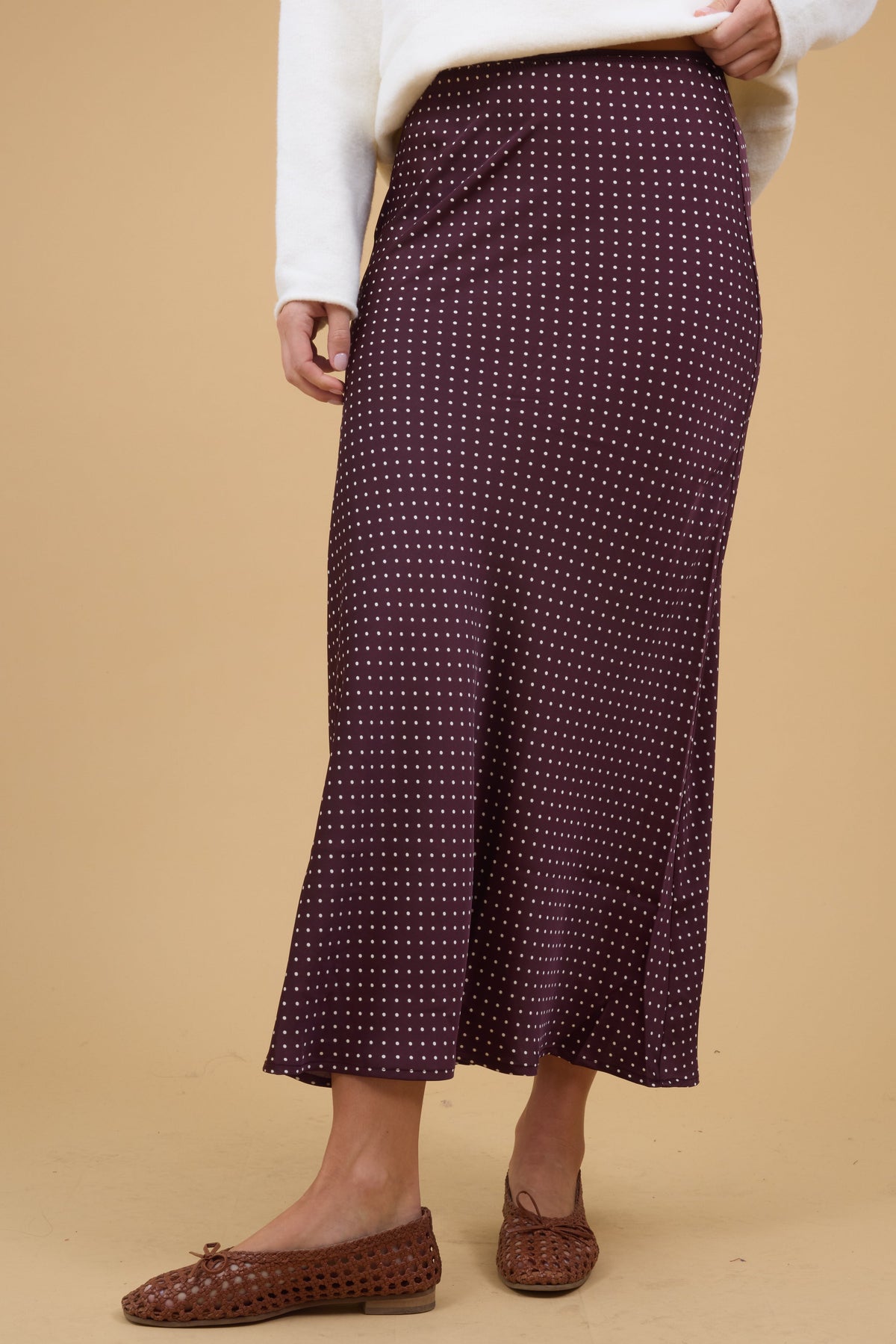 Young woman wearing a modest brown polka dot, A-line midi skirt.