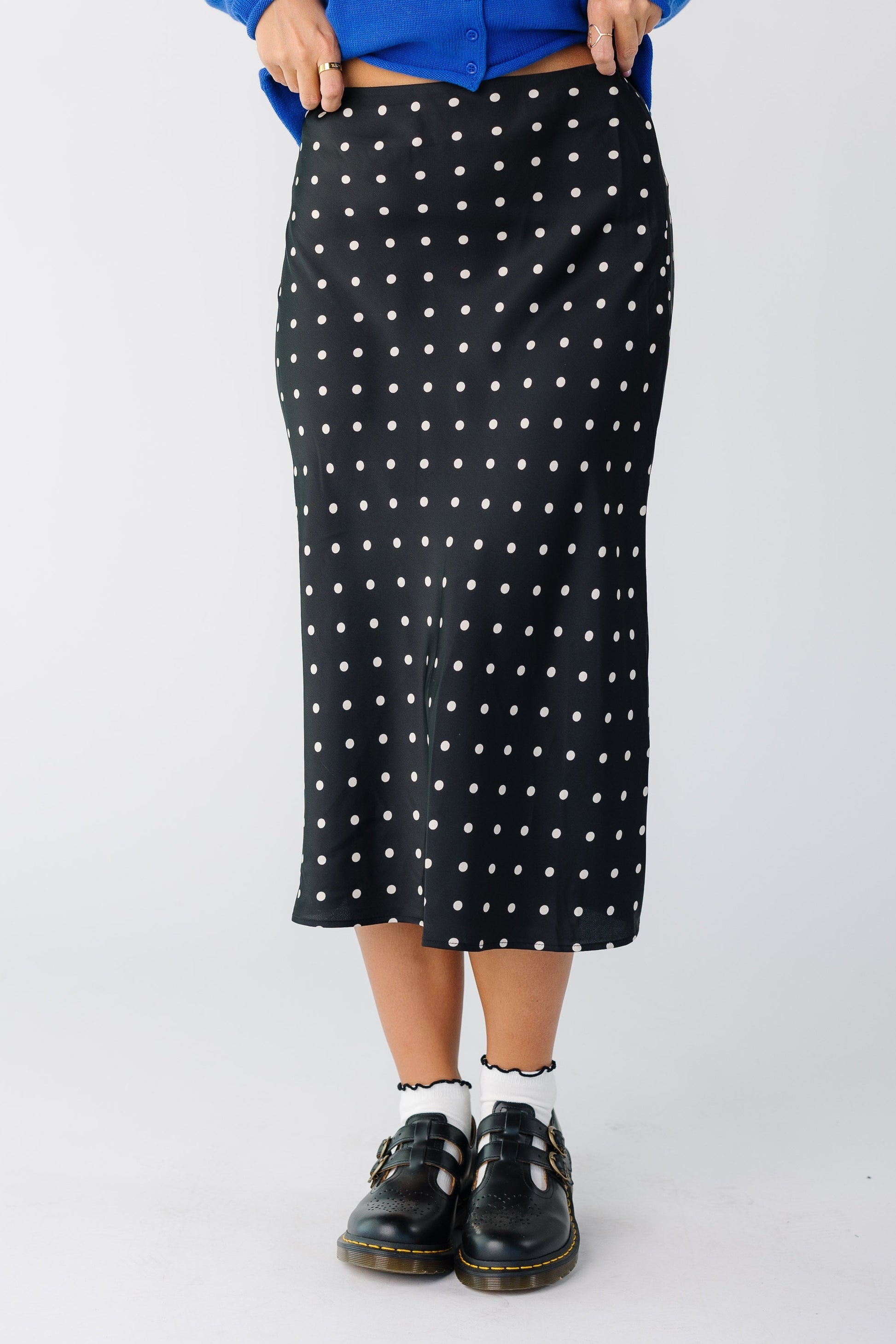 Woman wearing a modest black A-line midi skirt with white polka dots