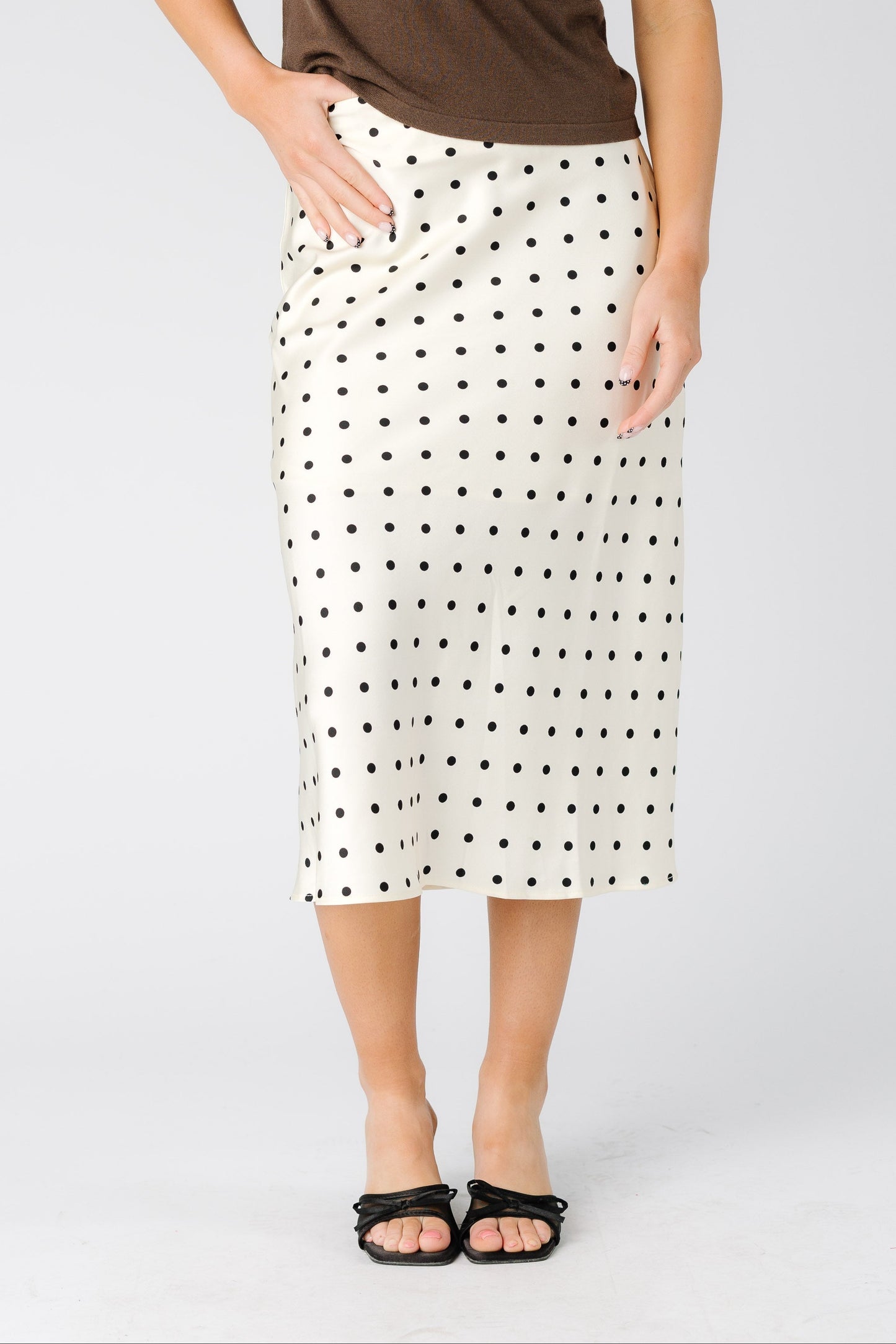 Woman wearing modest A-line midi skirt in cream with black polka dots