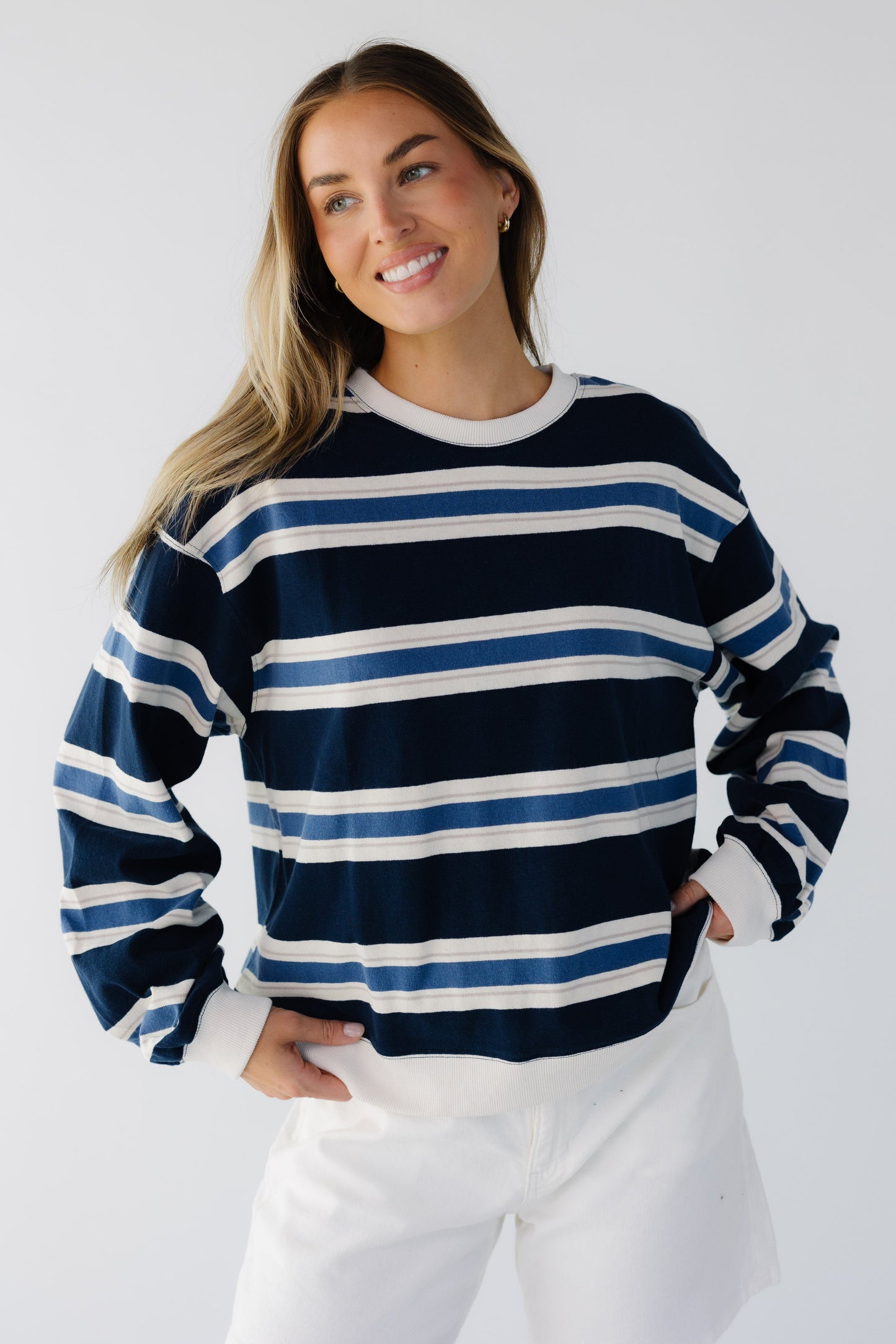Young woman wearing a blue multi color stripe loose fittting sweatshirt.