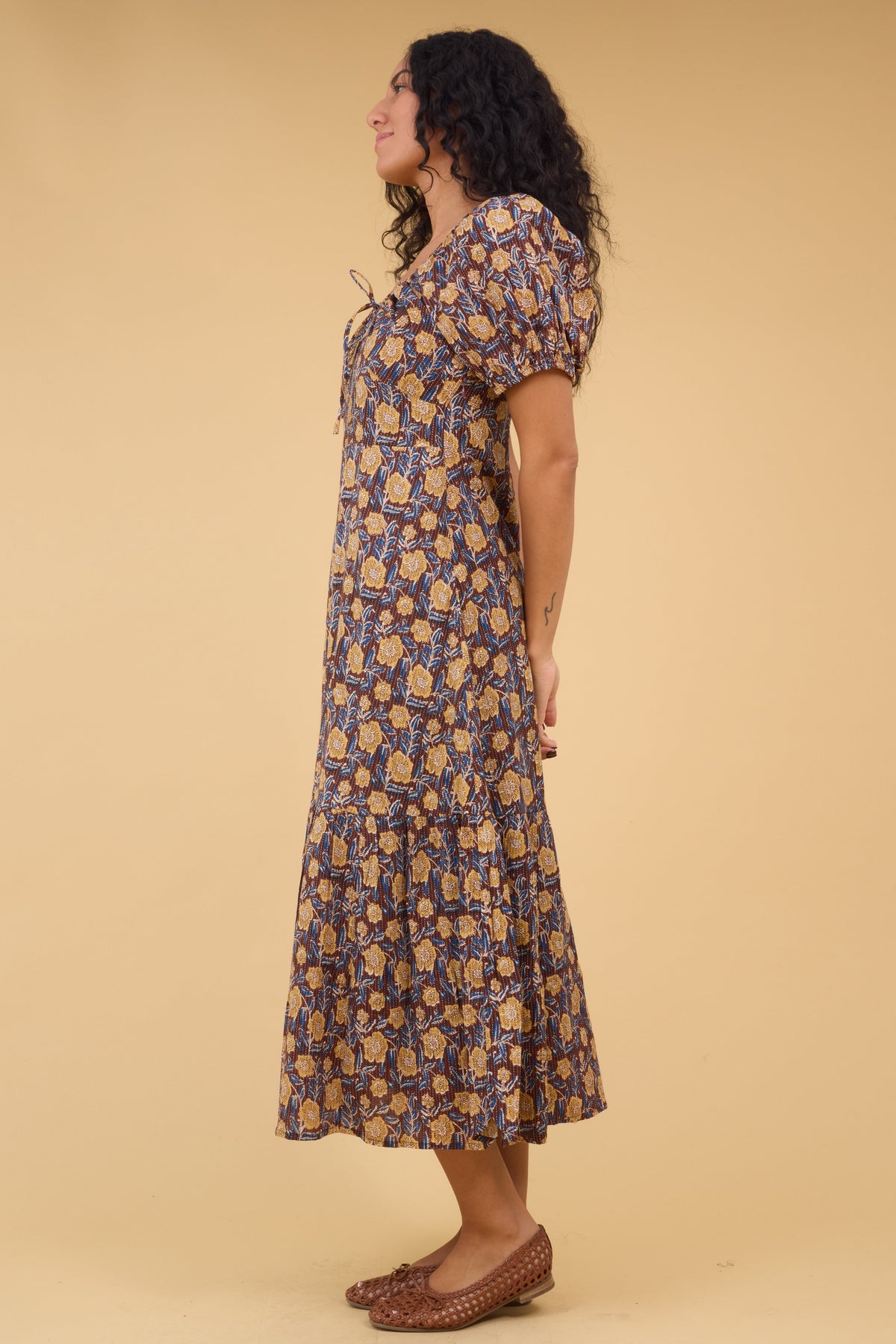 Side view of a woman wearing a floral print midi dress with large puff sleeves.