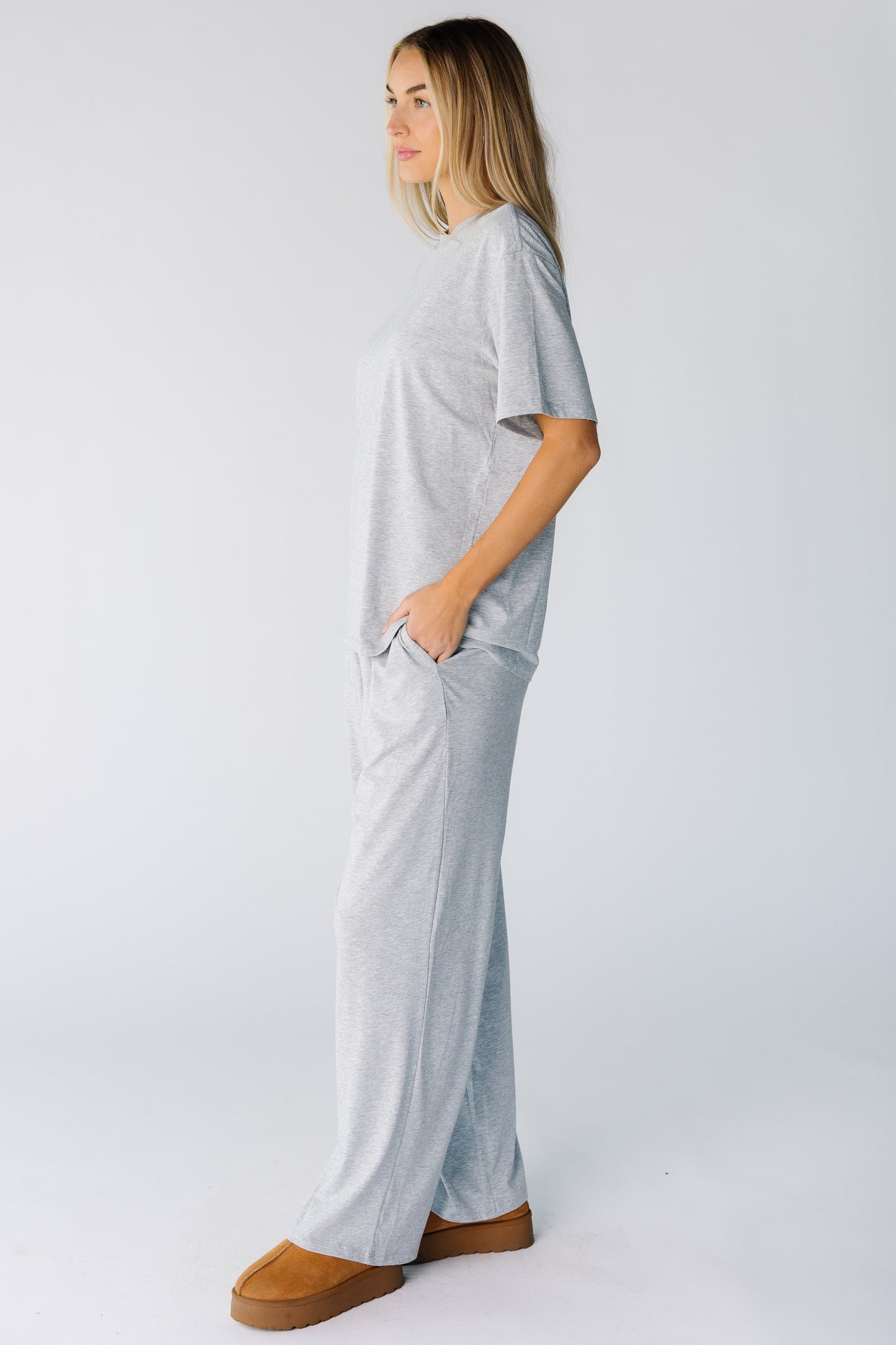 Side view of a woman wearing a heather grey lounge set with short sleeves and wide cut lounge pants with pockets