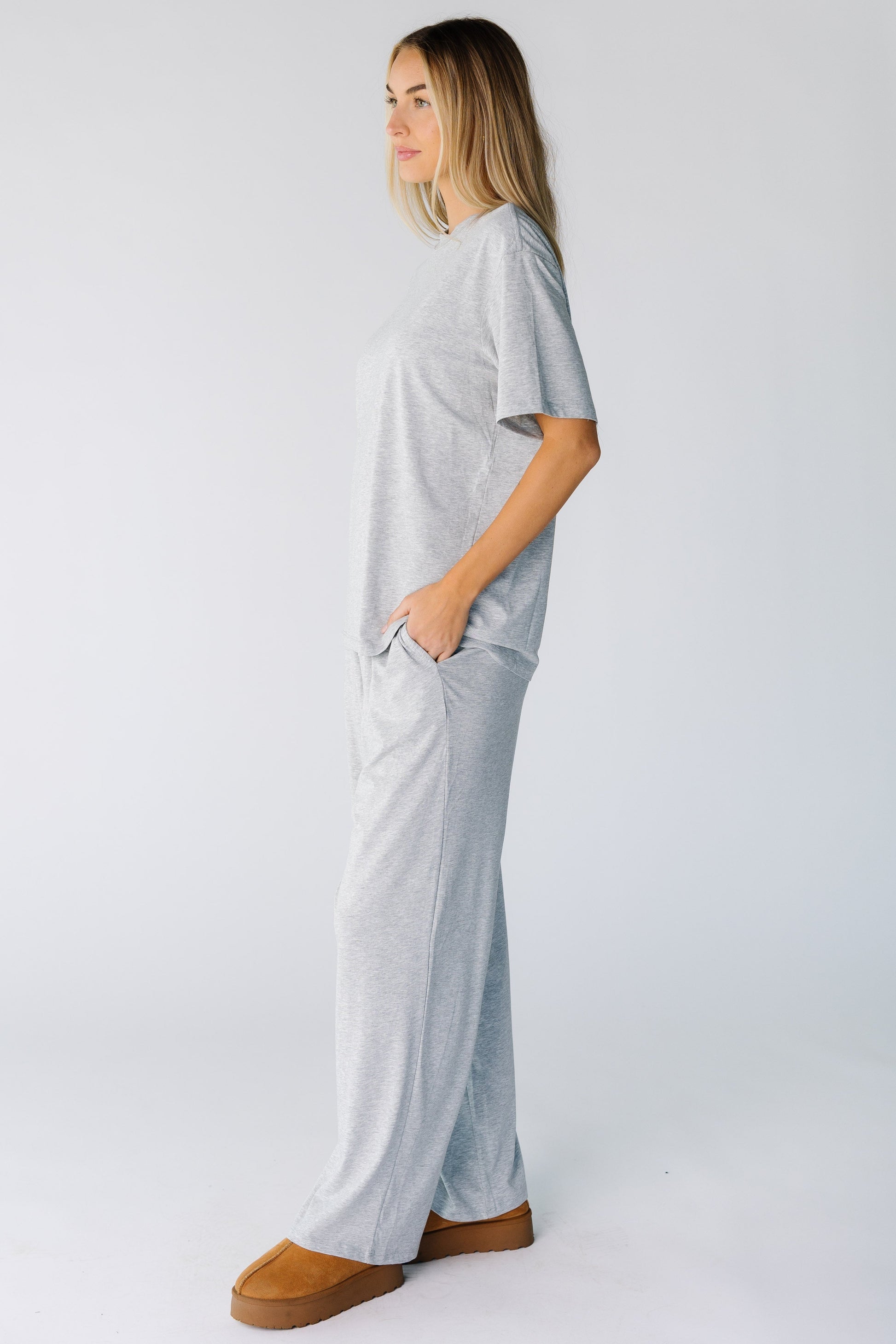 Side view of a woman wearing a heather grey lounge set with short sleeves and wide cut lounge pants with pockets