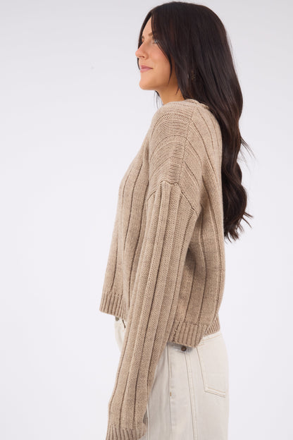 A woman wearing a wide ribbed cardigan with lnog sleeves.