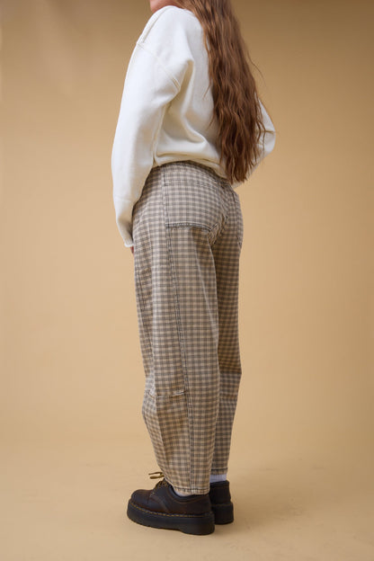 Back view of a woman wearing wide leg pants in brown with large back pockets.