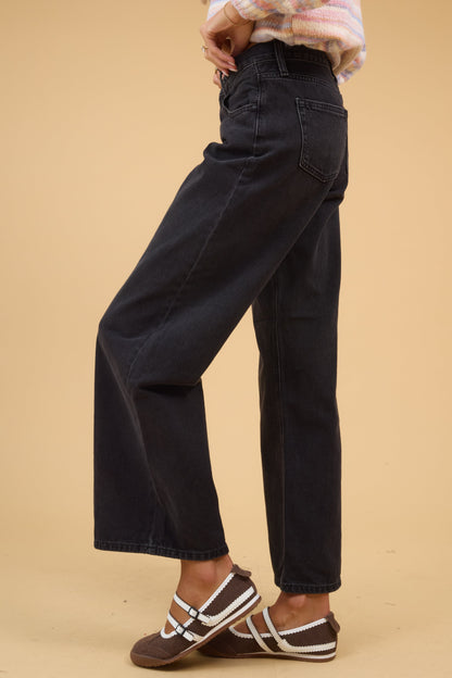 Young woman wearing modest wide leg jeans in washed black.