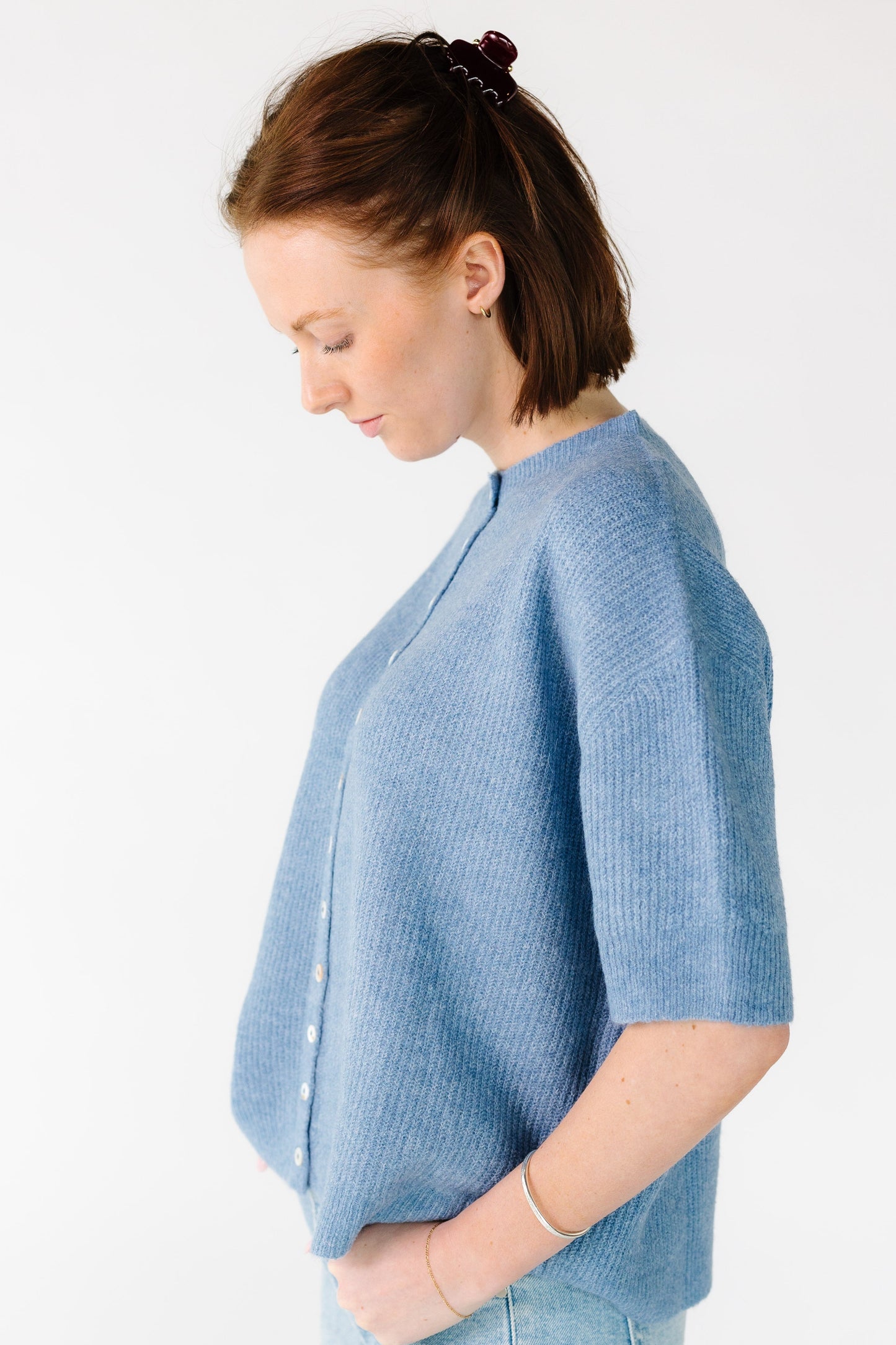 Side view of a woman wearing a loose fitting cardigan with short sleeves.