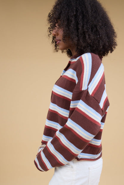 Side view of a woman wearing a brown & multicolor stripe cardigan with long sleeves.