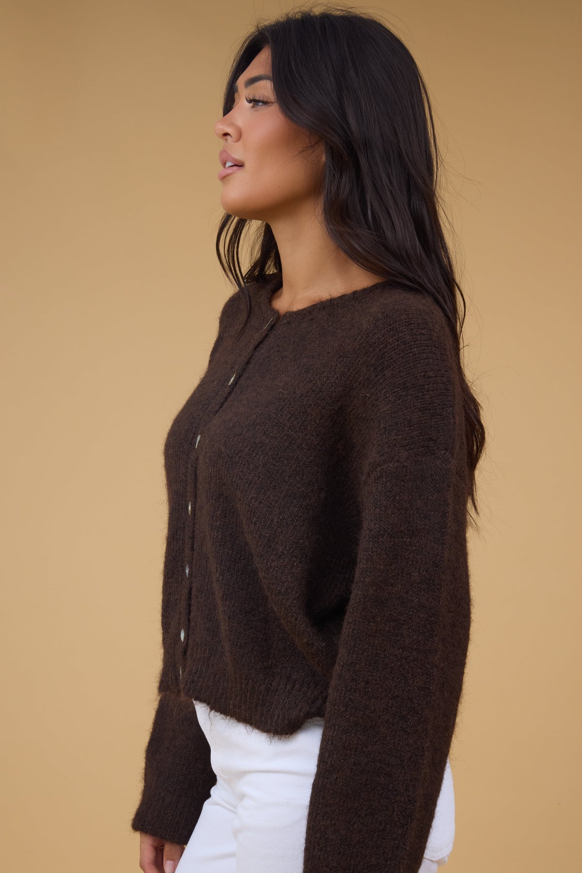 Side view of a woman wearing a long sleeve brown cardigan.