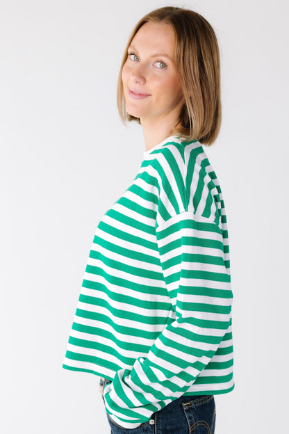 Side view of a woman wearing a green and white stripe top with a drop shoulder and long sleeves