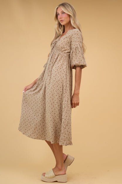 Side view of a young woman wearing a tan floral midi dress with half length sleeves and an empire waist.