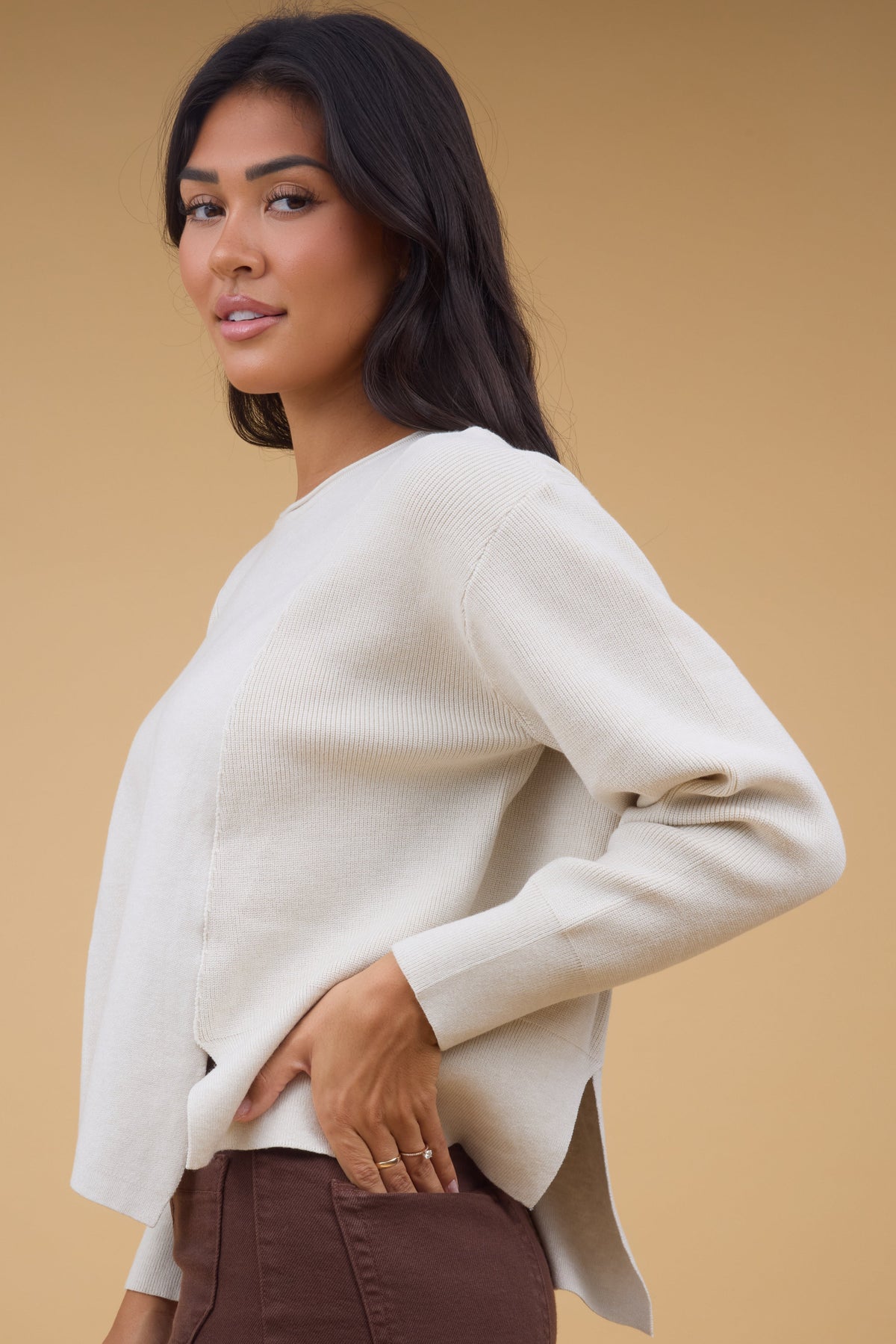 Side view of a woman wearing a 2 fabric knit top with ribbed side panel and smooth knit front.