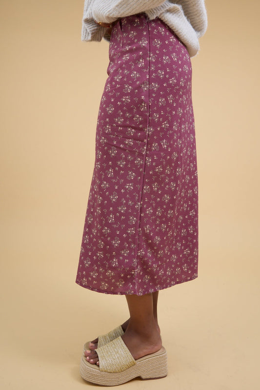 Young woman wearing a pink floral print, A-line midi skirt.