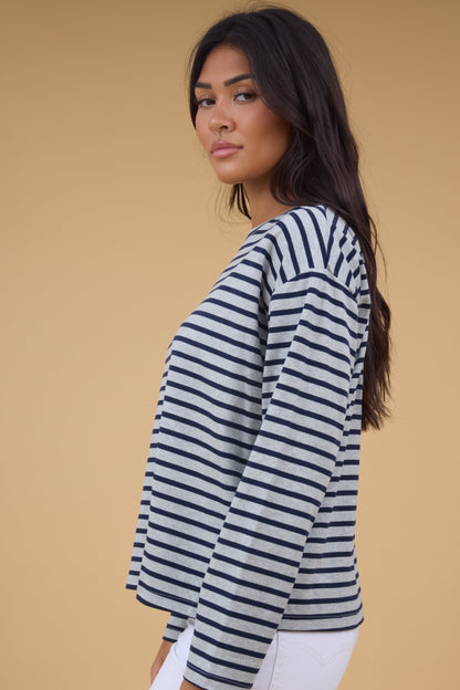 Side view of a woman wearing a grey & navy stripe, long sleeve tee.