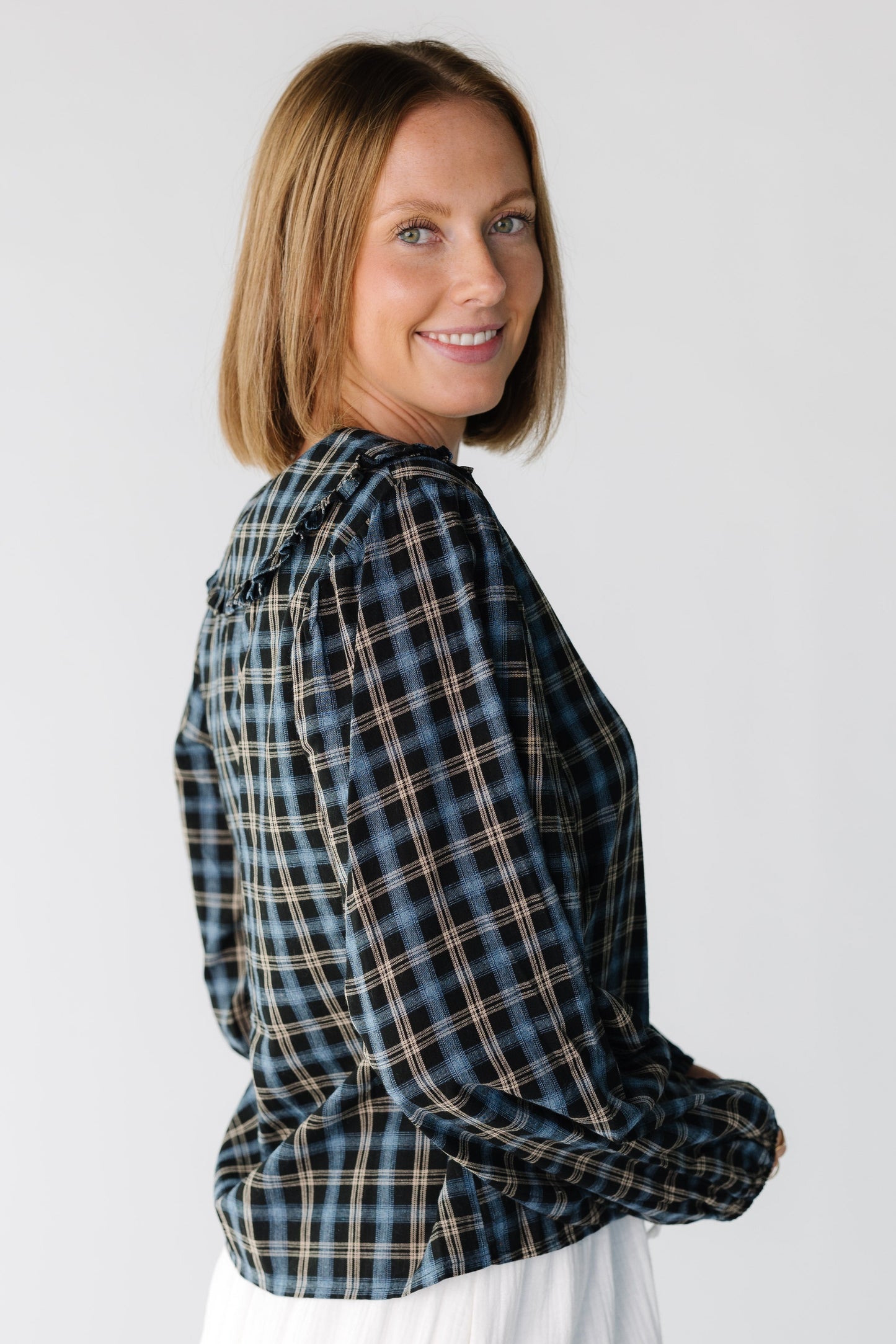 Side view of a woman wearing a navy plaid top with long sleeves