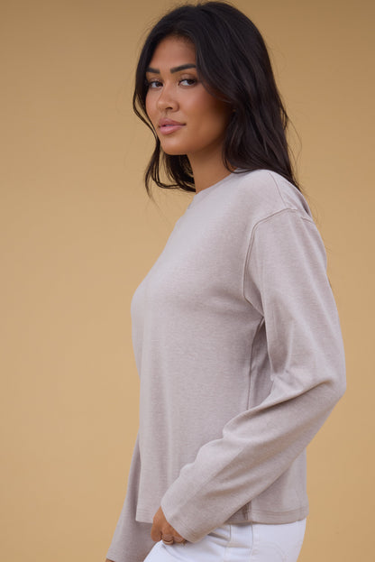 A woman wearing a light knit top with long sleeves.