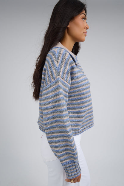 Side view of a woman wearing a taupe-blue multi stripe cardigan with long sleeves.