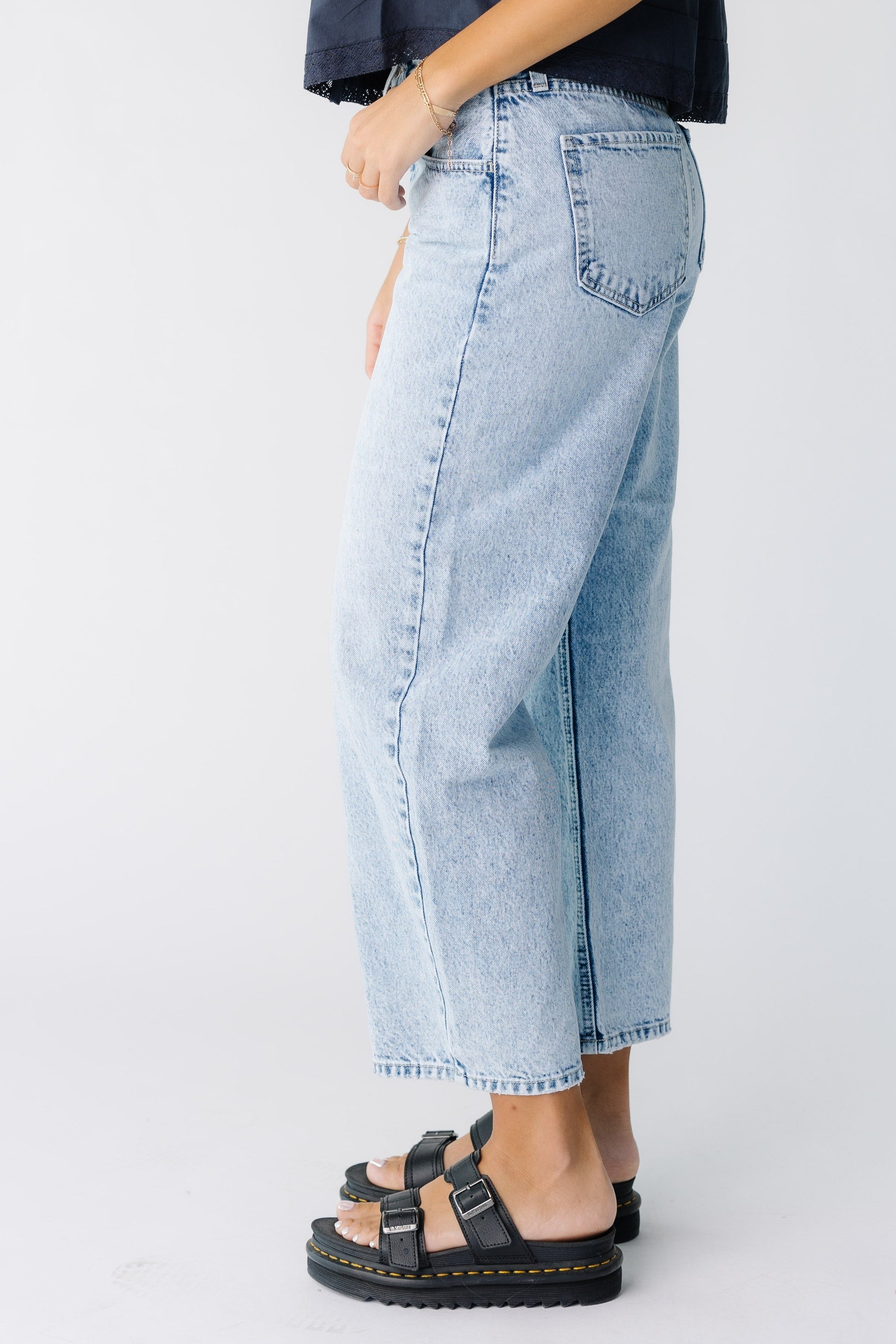 Side view of a woman wearing  a pair of light denim wide leg jeans.
