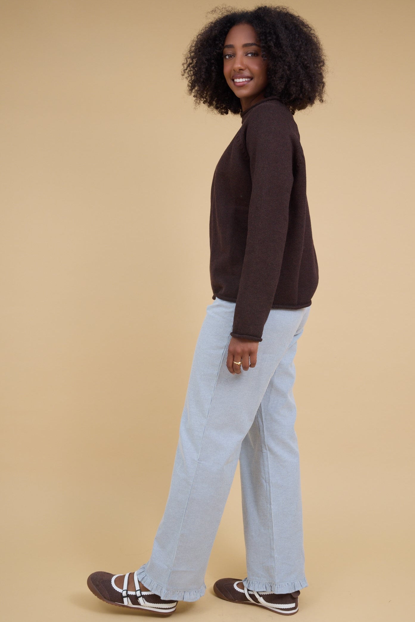 Womann wearing a pair of wide leg navy & white stripe pants with narrow ruffle hems.
