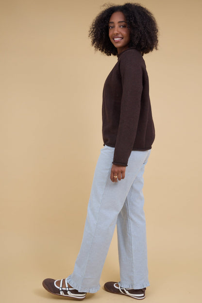 Womann wearing a pair of wide leg navy & white stripe pants with narrow ruffle hems.