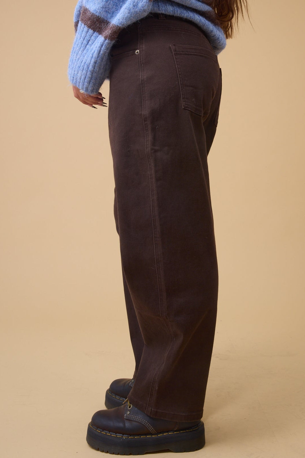 Side view of a woman wearing  brown wide leg pants with pockets