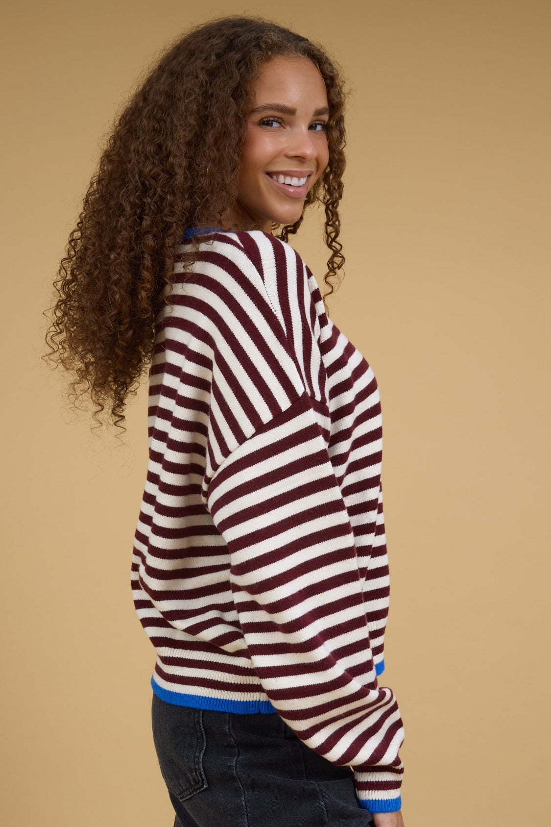 Side view of a teenage girl wearing a modest burgundy & cream stripe top with contrasting blue hems