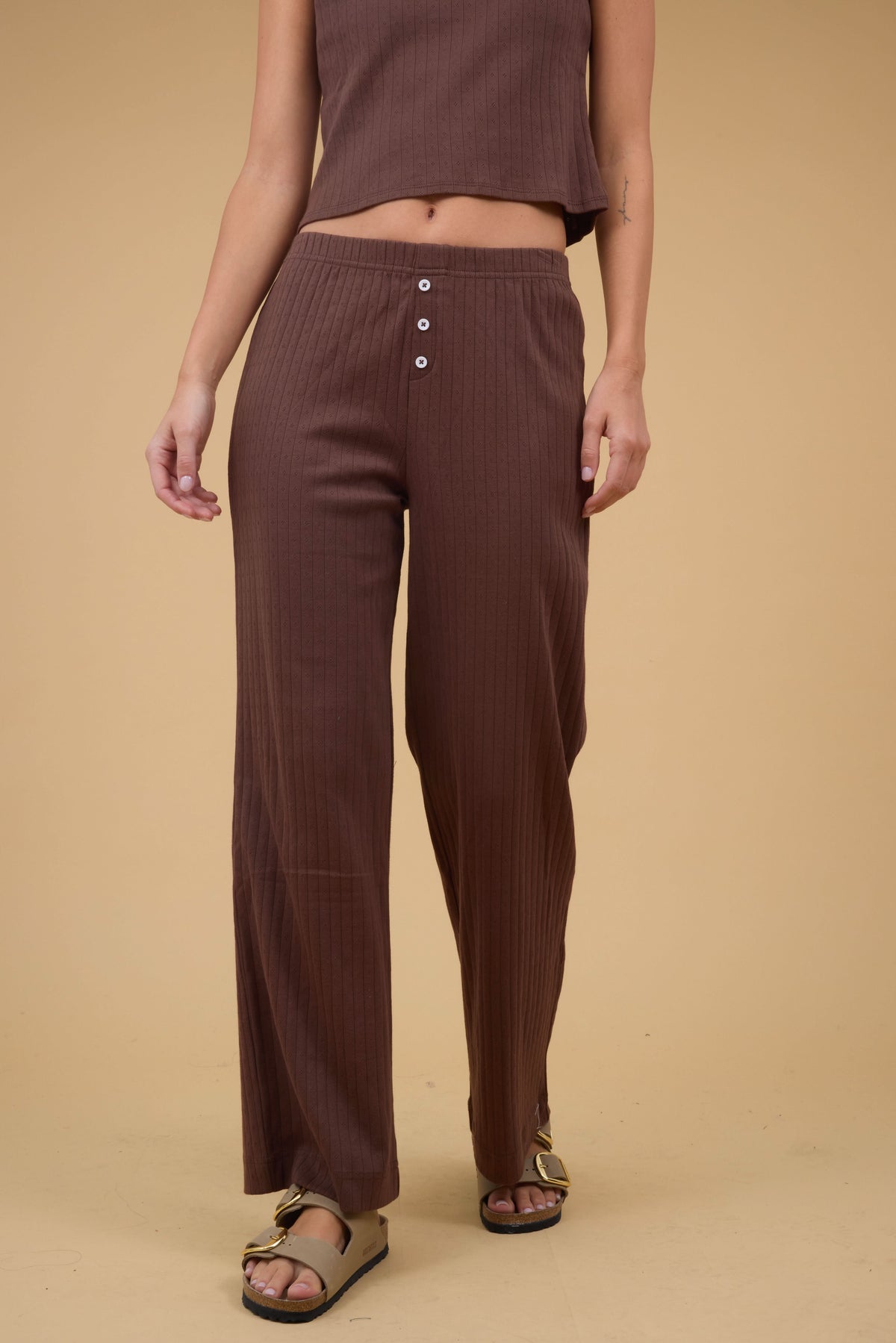 A young woman wearing a modest pair of brown pointelle knit, wide leg pants.