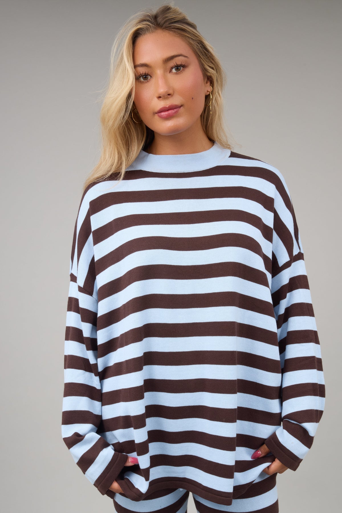 Woman wearing a brown & light blue wide stripe top with long sleeves.