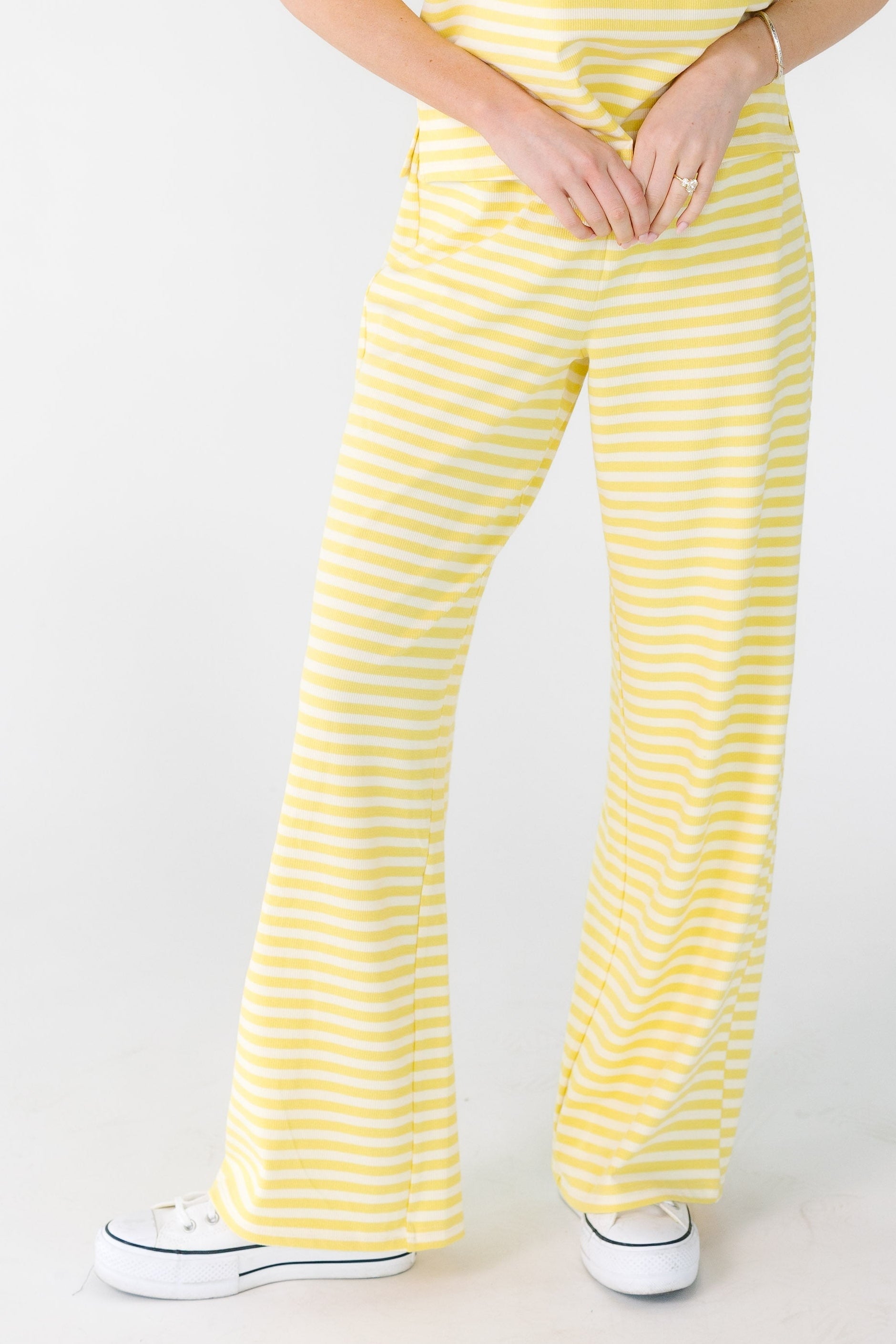 Young woman wearing straight cut lounge pants in yellow and white stripe.