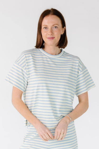 Woman wearing a light blue and white stripe rib knit top with a crew neckline and short sleeves.