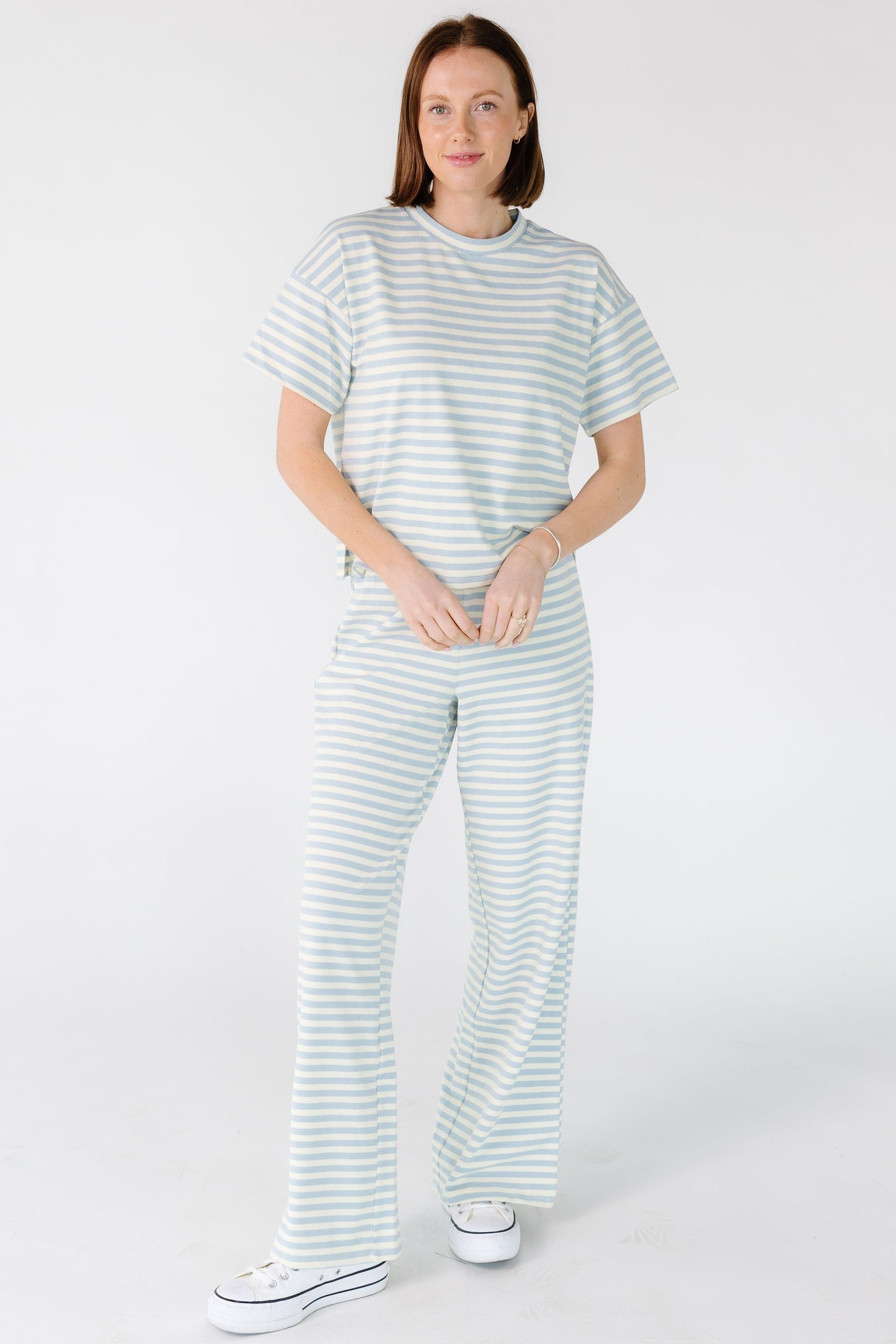 Young woman wearing a light blue and white stripe, straight cut lounge pants.