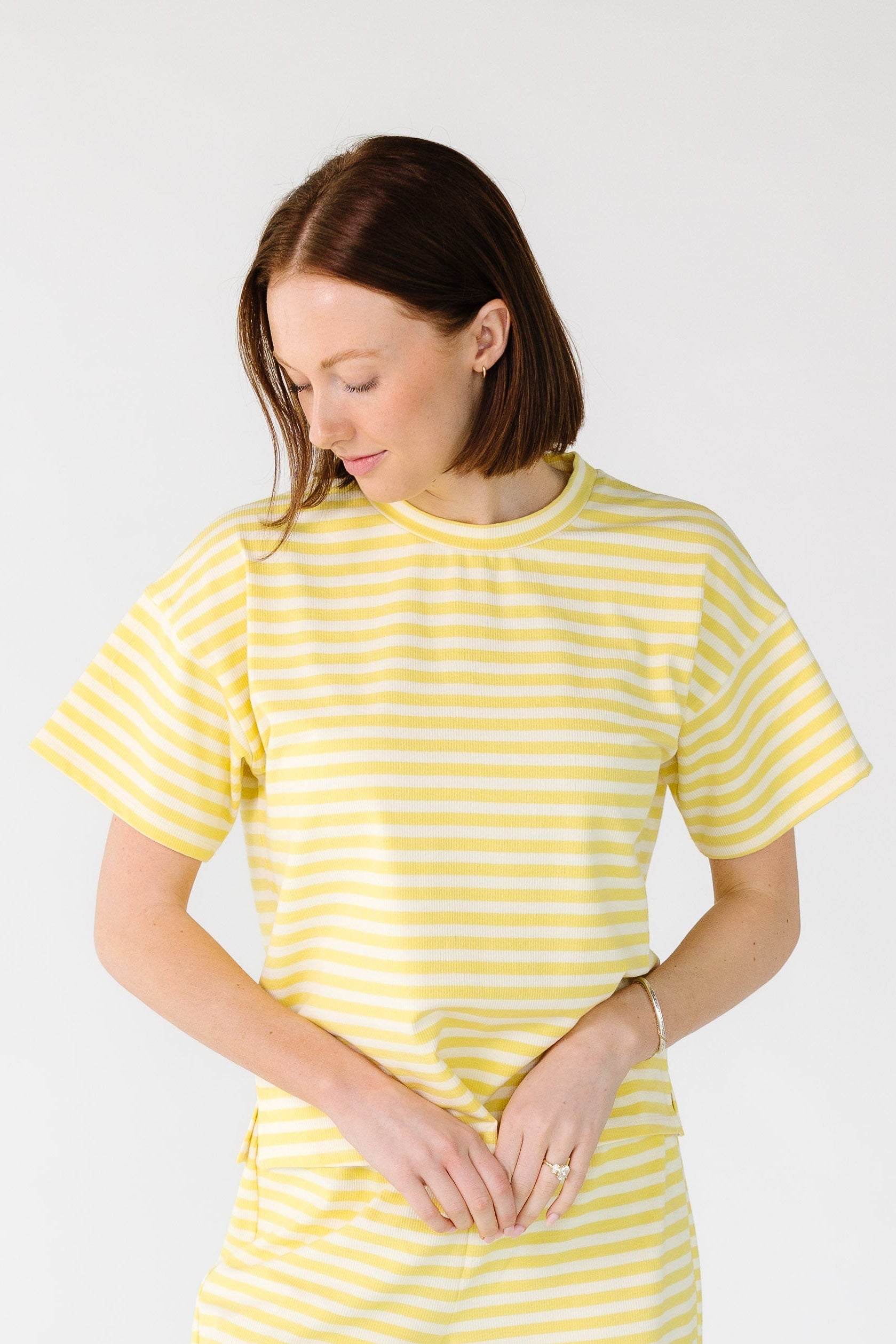 Woman wearing a yellow and white stripe rib knit top with short sleeves.