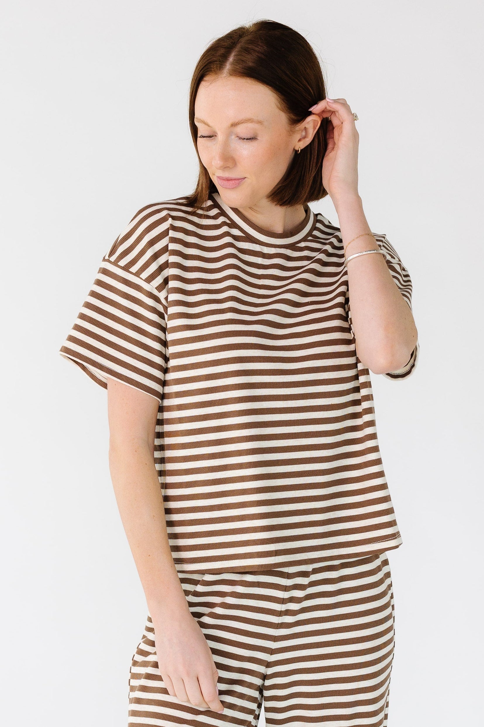 Young woman wearing a cream and brown stripe rib knit top with short sleeves.
