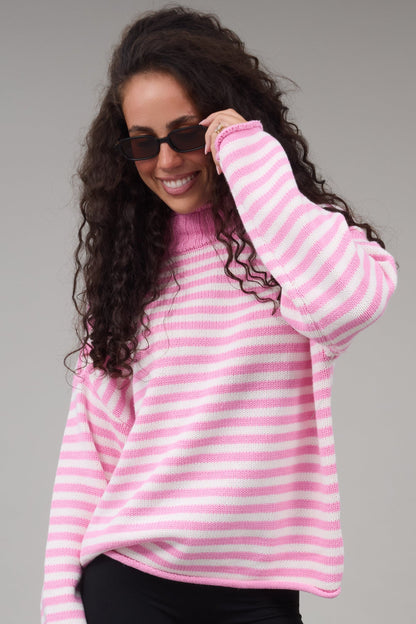 Young woman wearing a pink & white stripe oversized sweater in with a turtle neckline.