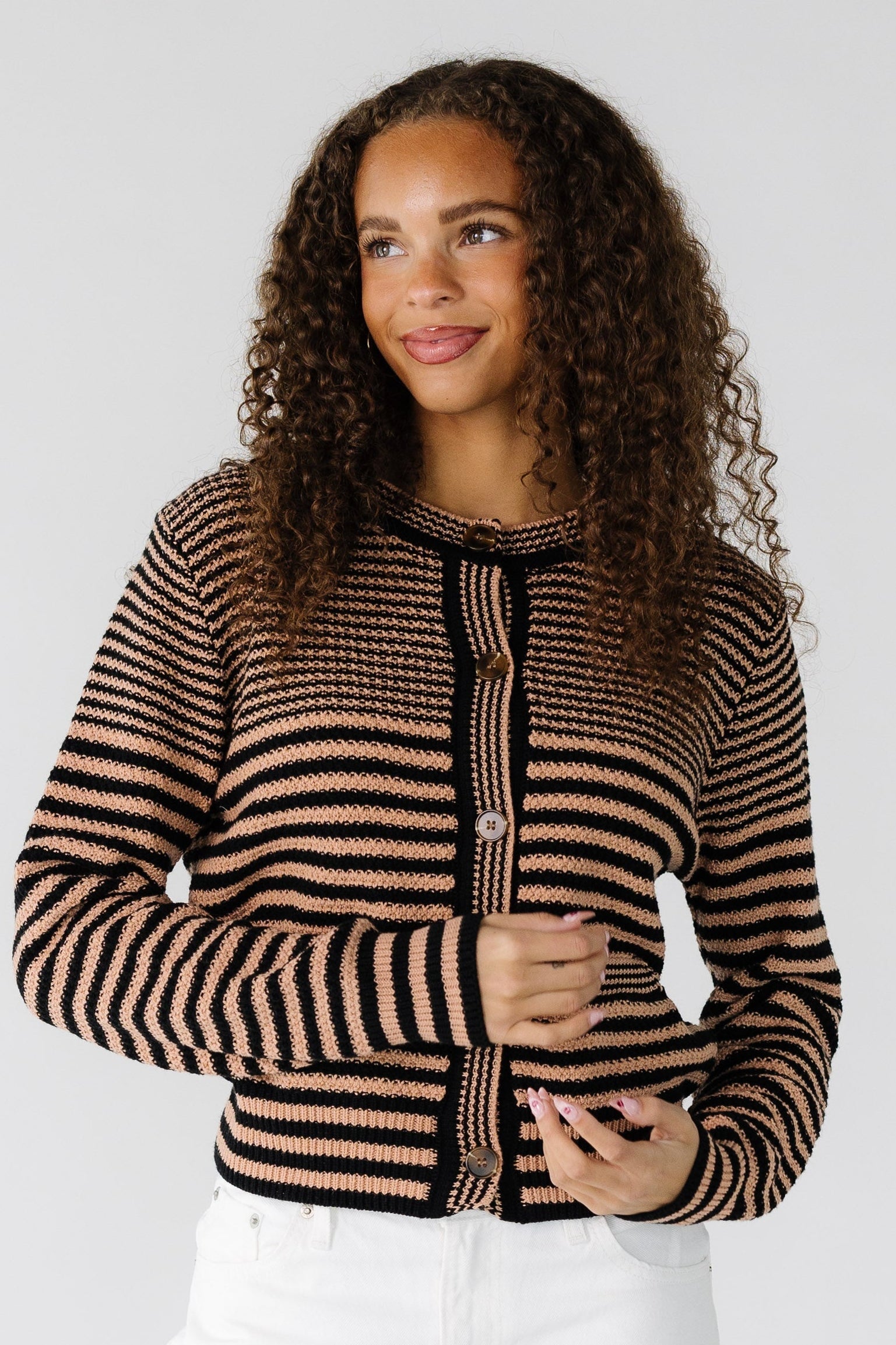 Teen girl wearing a modest taupe and black horizontal stripe cardigan with long sleeves and a round neckline.