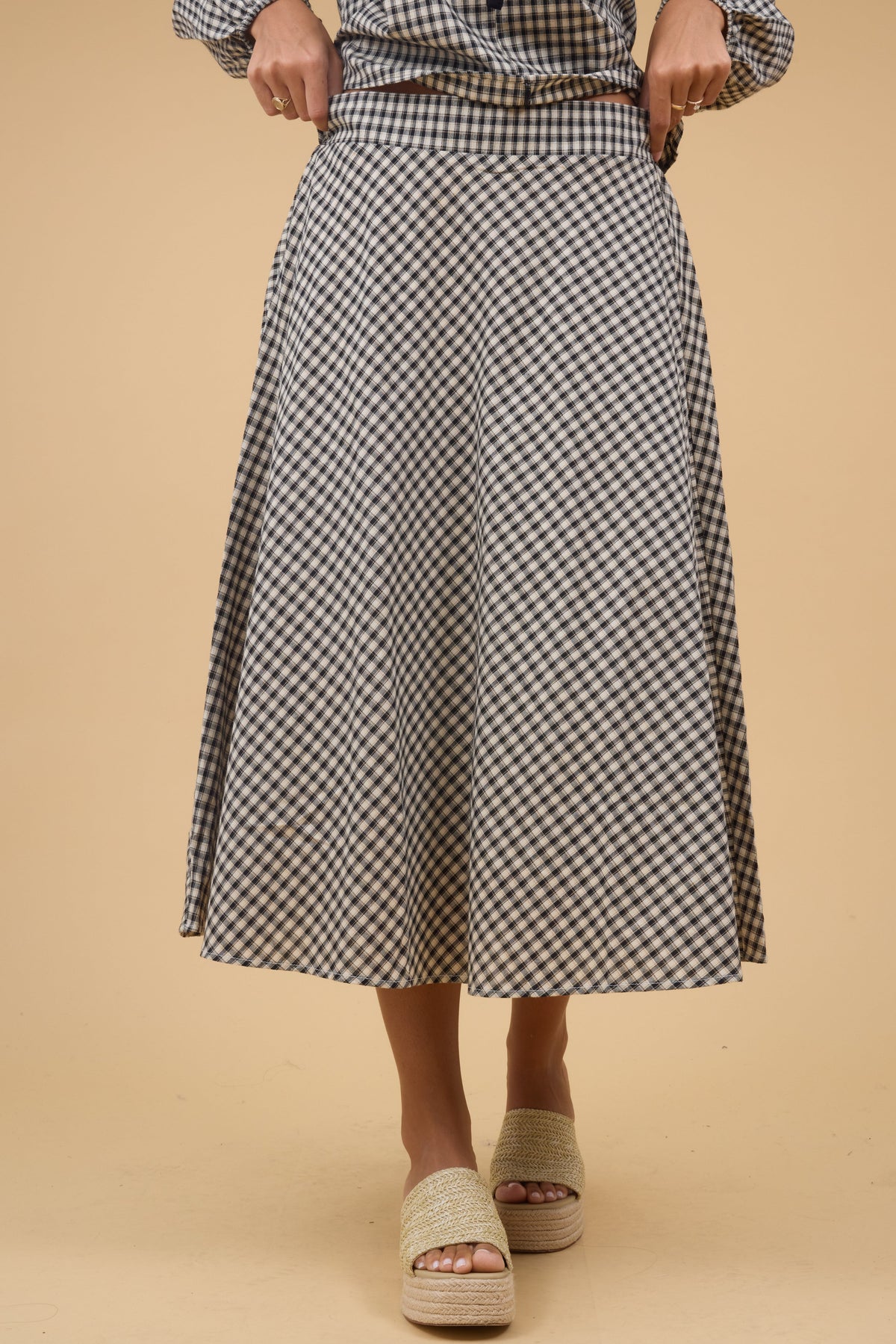 Young woman wearing a modest tan & black, plaid A-line midi skirt with a wide waistband.
