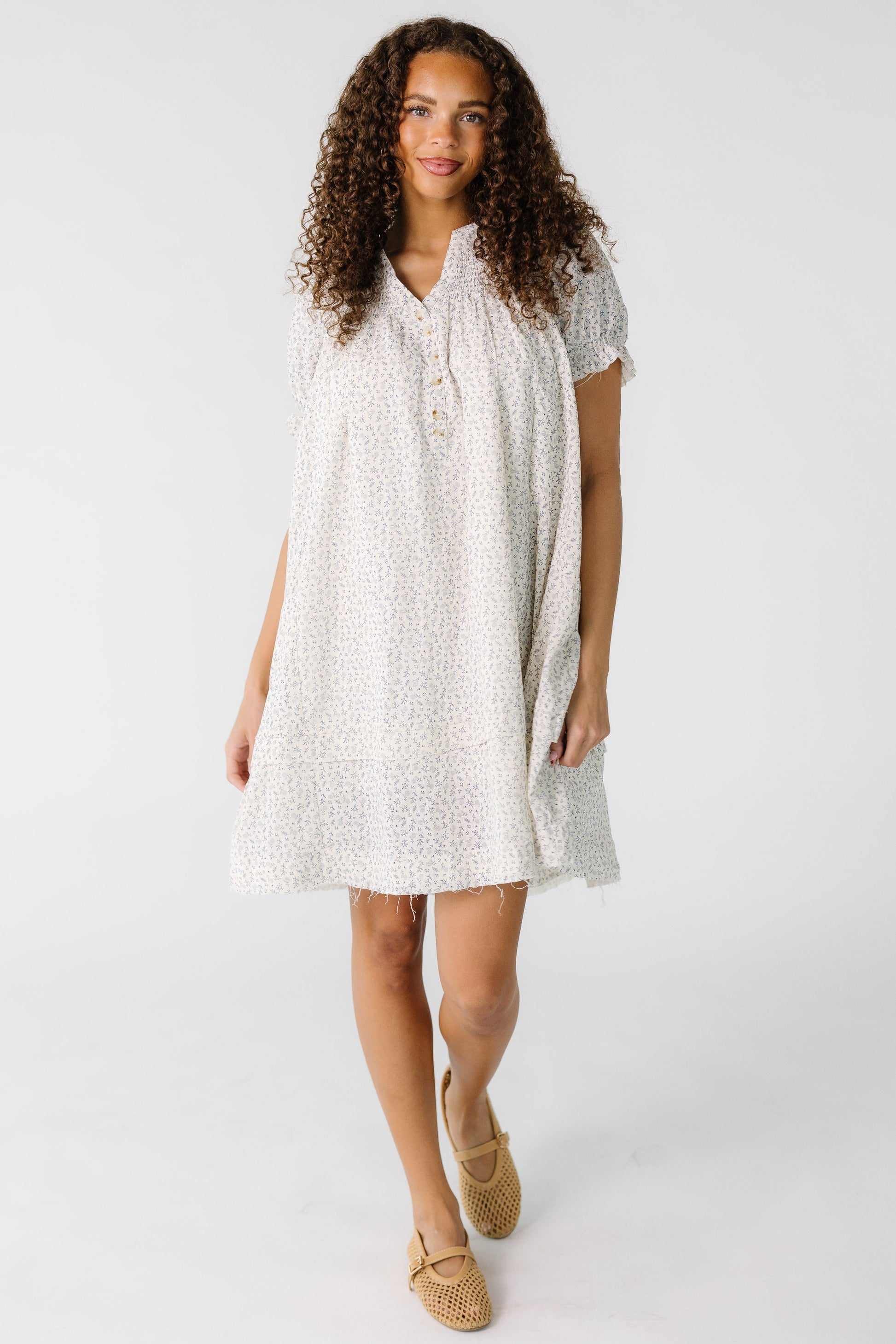 Teen girl wearing a white and grey print short dress with scissor cut hems.