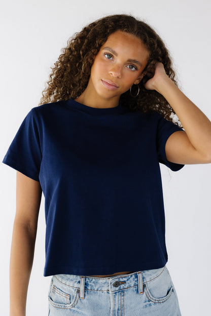 Teenage girl wearing a navy boxy cut navy short sleeve tee.