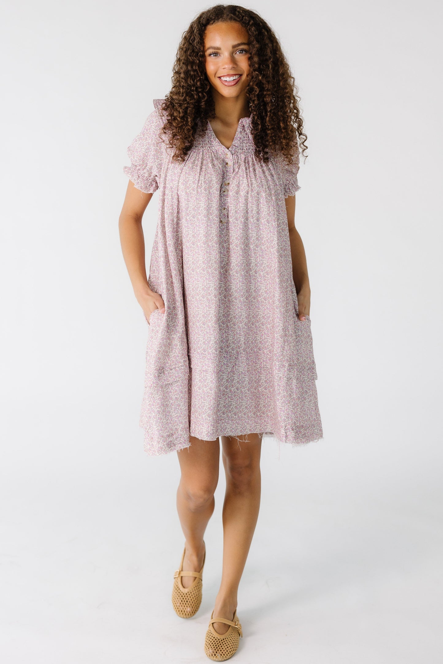 Teenage girl wearing a pink floral dress with a v-neckline, wide collar and smocked front yoke.