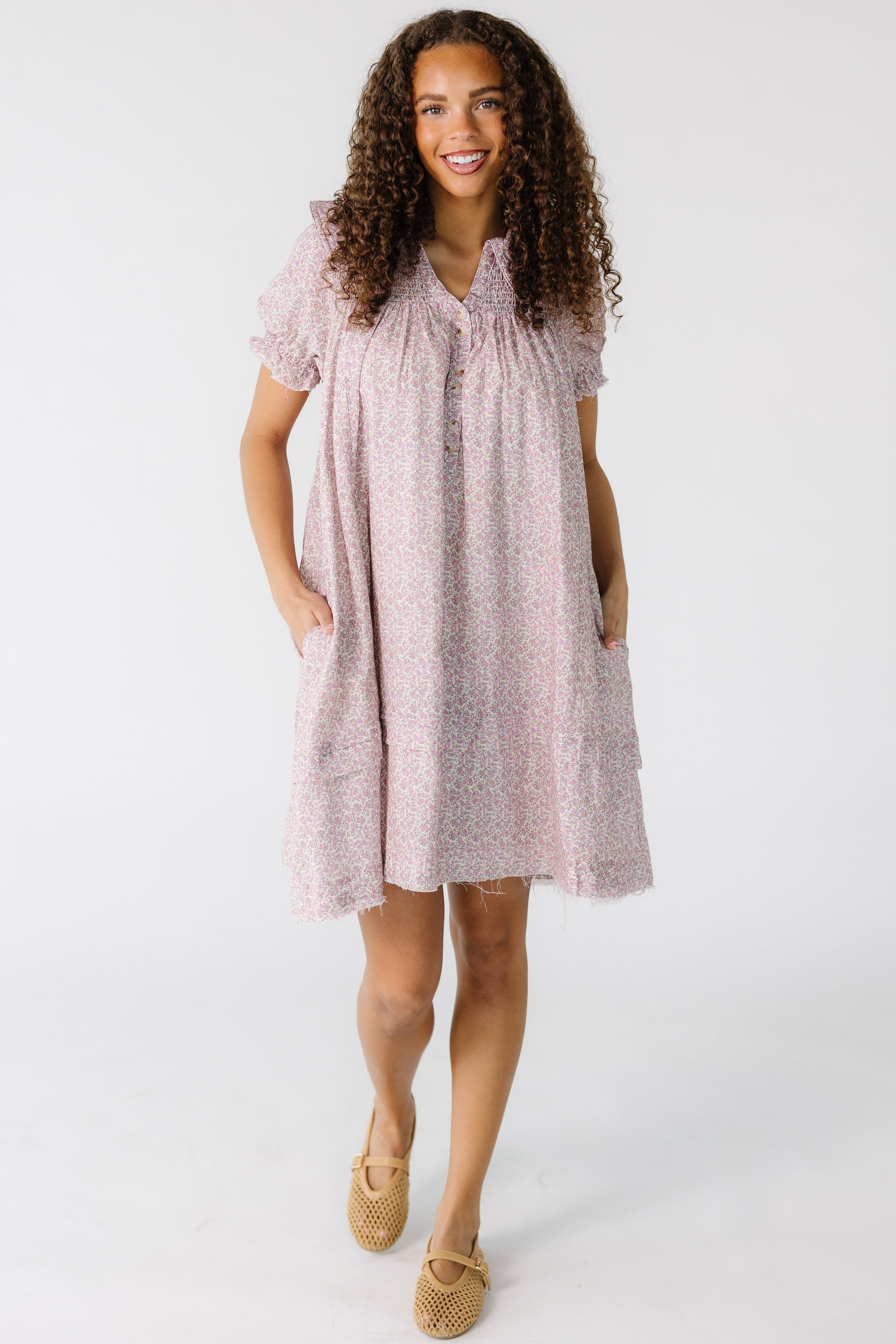 Teenage girl wearing a pink floral dress with a v-neckline, wide collar and smocked front yoke.