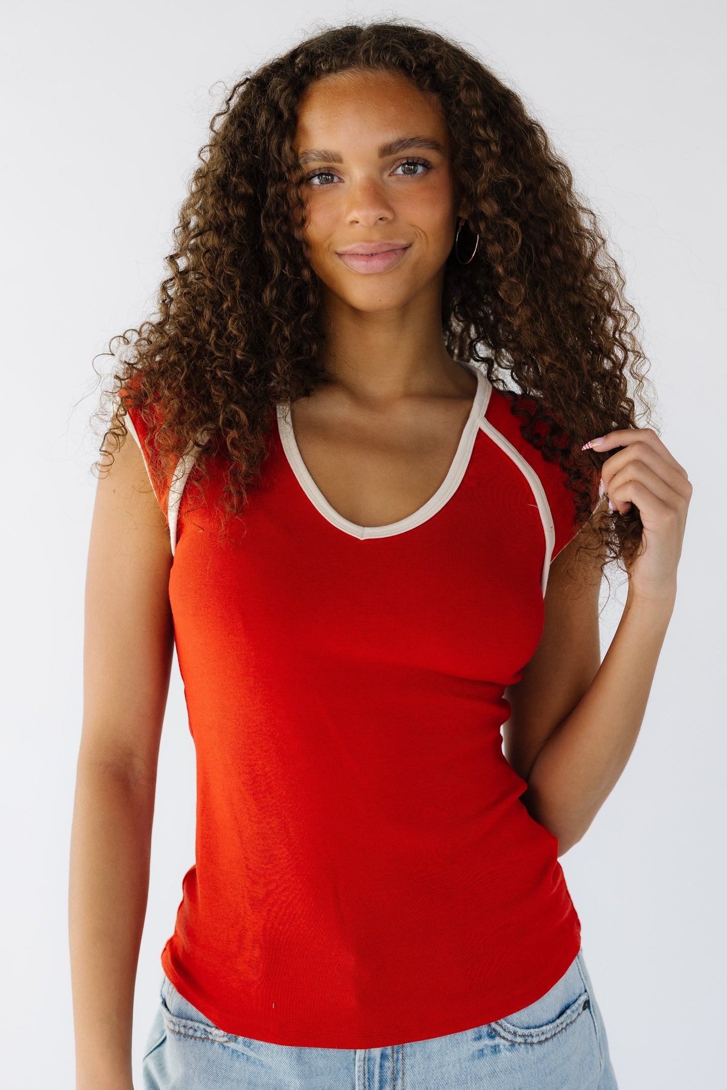 Teenage girl wearing a close fitting rib knit top with cream trimmed neckline and sleeves.