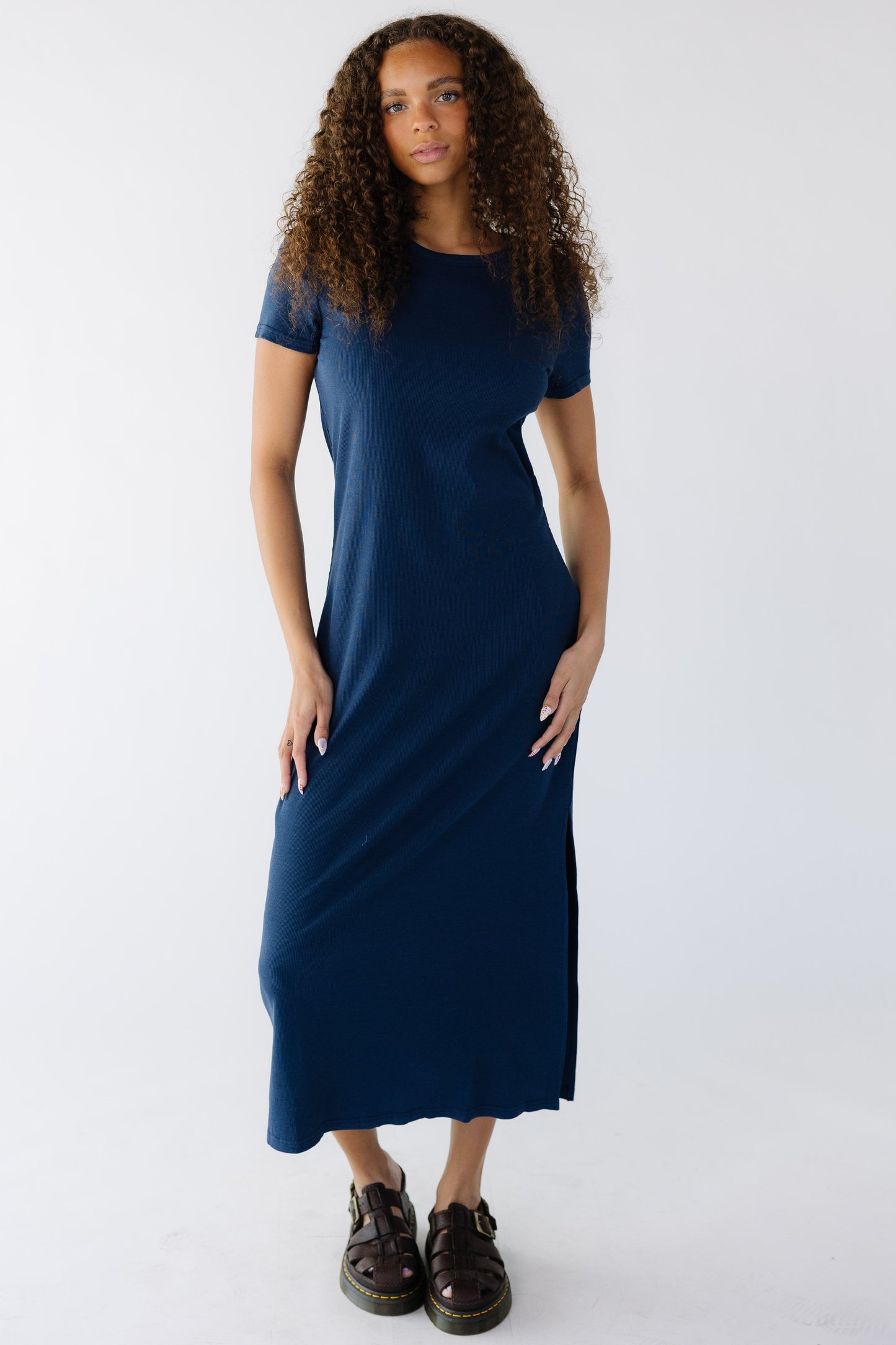 Teen girl wearing a navy rib knit midi dress with short sleeves and a slight scoop neckline.